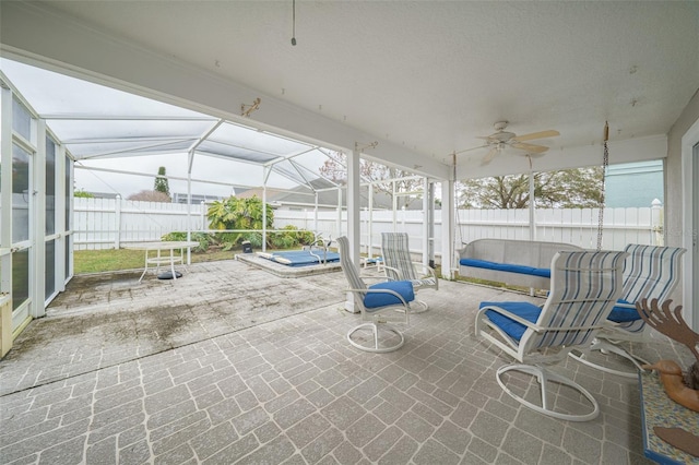 view of patio / terrace featuring a ceiling fan, glass enclosure, a fenced backyard, and a jacuzzi