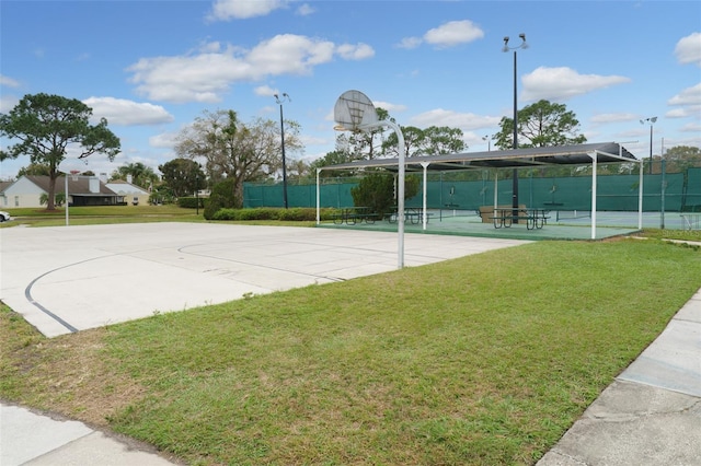 view of basketball court with a yard, community basketball court, and fence