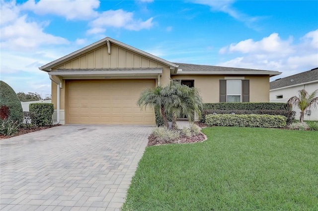 single story home with a garage, decorative driveway, stucco siding, a front lawn, and board and batten siding