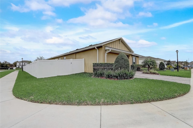 view of home's exterior featuring a garage, fence, driveway, a lawn, and board and batten siding