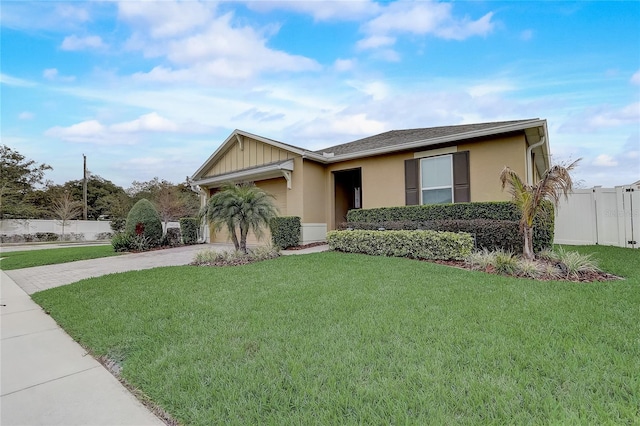 ranch-style house featuring a front lawn, driveway, an attached garage, and fence