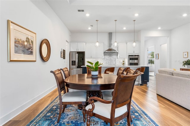 dining area with light wood finished floors, recessed lighting, visible vents, and baseboards