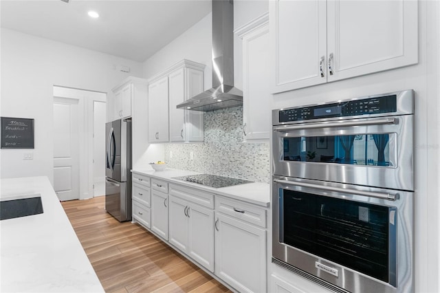 kitchen featuring stainless steel appliances, backsplash, light countertops, and wall chimney range hood