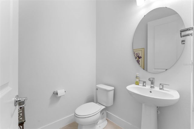 half bathroom featuring tile patterned flooring, baseboards, and toilet