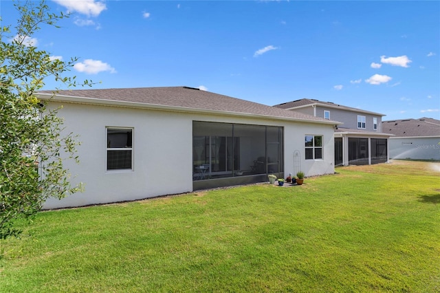 rear view of property with a sunroom, stucco siding, and a yard