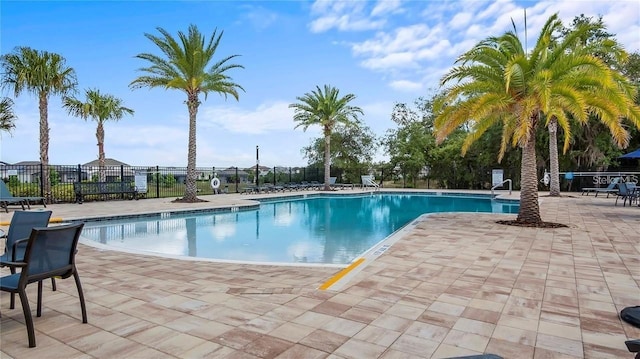 community pool with a patio and fence