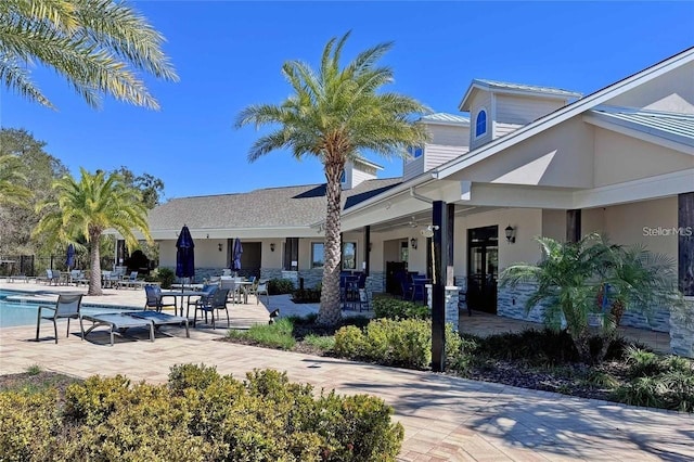 exterior space with a patio, a community pool, and stucco siding