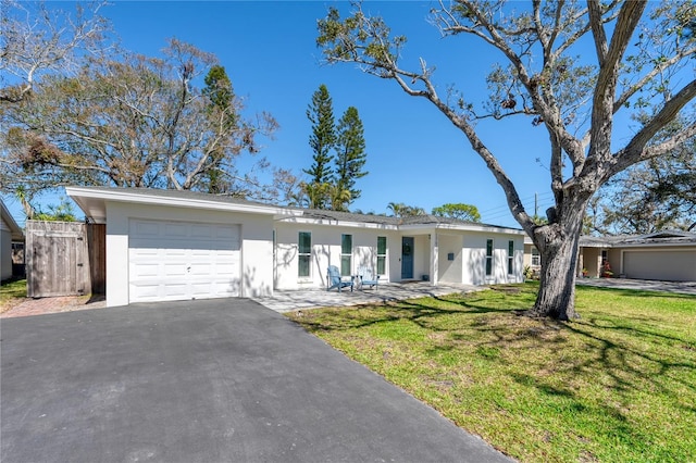 ranch-style house featuring a garage, aphalt driveway, a front lawn, and stucco siding