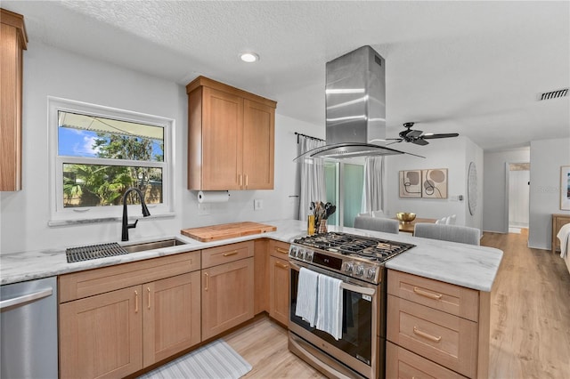 kitchen featuring visible vents, appliances with stainless steel finishes, open floor plan, island exhaust hood, and a sink