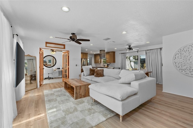 living area with light wood-style flooring, visible vents, a textured ceiling, and recessed lighting