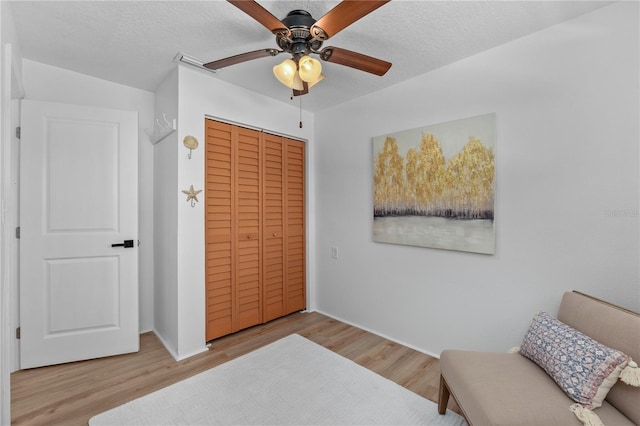 living area featuring ceiling fan, a textured ceiling, and wood finished floors