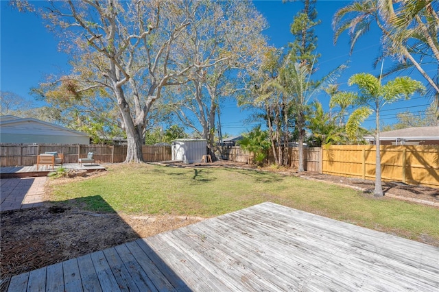 wooden deck with an outbuilding, a fenced backyard, a yard, and a storage unit