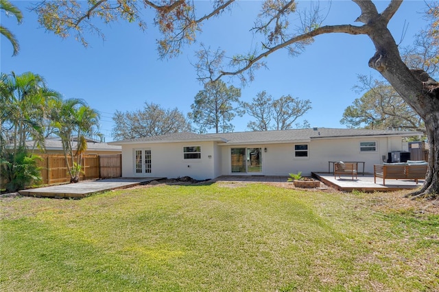 rear view of property featuring a yard, french doors, fence, and a wooden deck