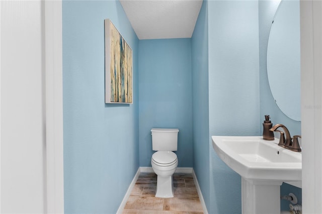 bathroom with a sink, toilet, and baseboards