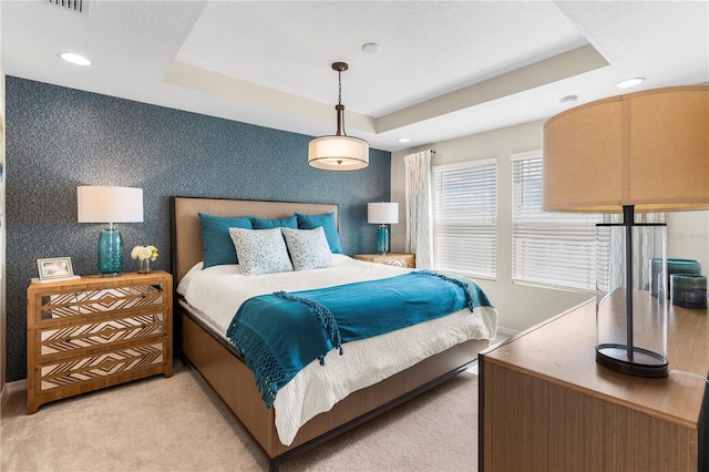 bedroom featuring light carpet, wallpapered walls, baseboards, and a raised ceiling