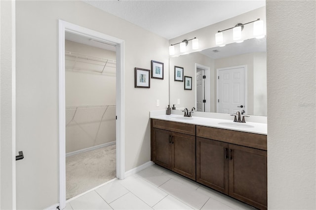 full bathroom featuring tile patterned floors, a sink, a spacious closet, and double vanity