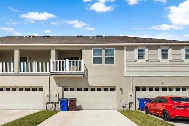 multi unit property featuring driveway, an attached garage, a balcony, and stucco siding