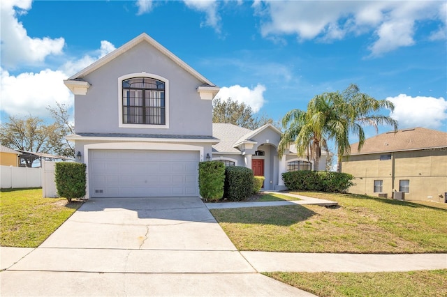 view of front facade with a front yard, fence, driveway, and stucco siding