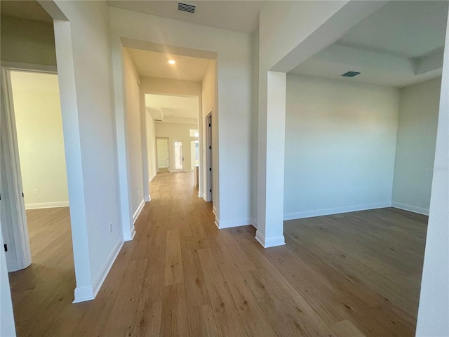 corridor with visible vents, baseboards, and wood finished floors