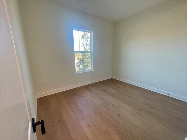 unfurnished room with baseboards and dark wood-style flooring