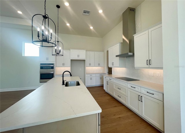 kitchen featuring double oven, black electric stovetop, a sink, visible vents, and wall chimney exhaust hood