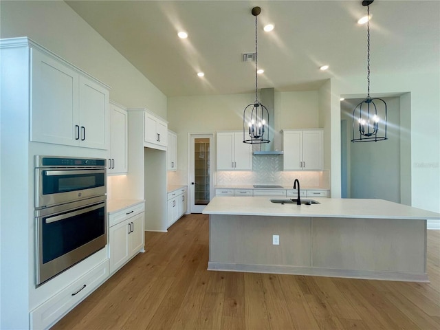 kitchen featuring visible vents, decorative backsplash, light wood-style floors, white cabinets, and a sink