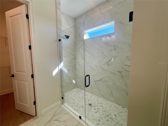 full bathroom featuring marble finish floor, a marble finish shower, and baseboards