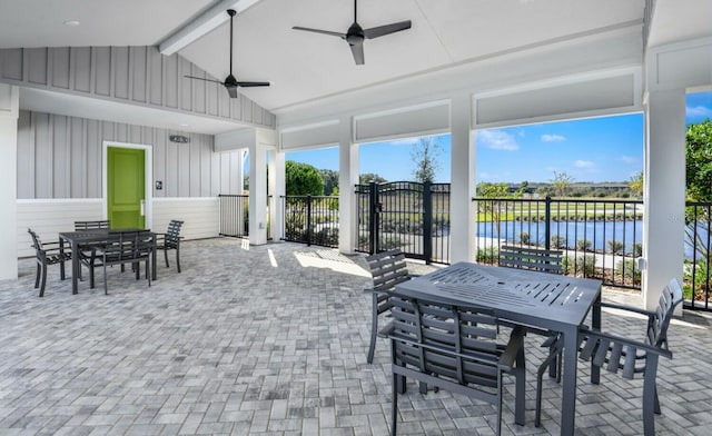 sunroom / solarium featuring a ceiling fan, a water view, and lofted ceiling with beams