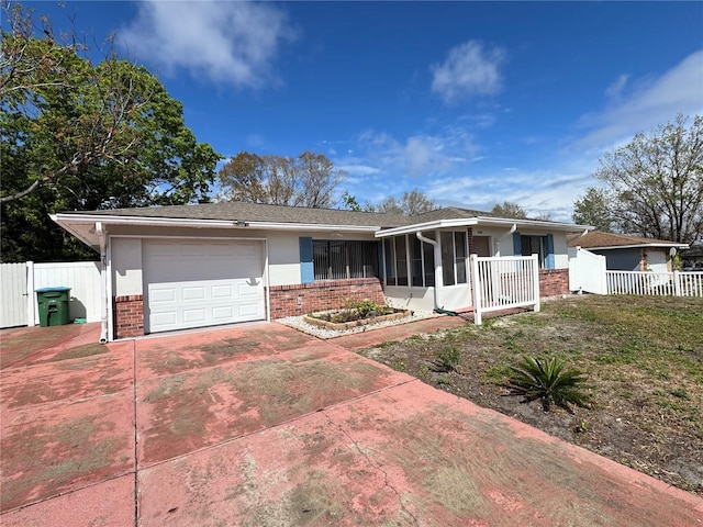 ranch-style home with a garage, driveway, brick siding, and fence