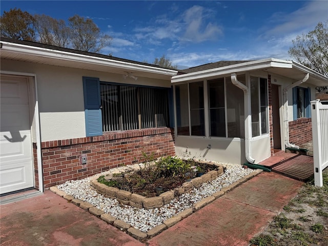 view of property exterior featuring a sunroom, brick siding, and stucco siding