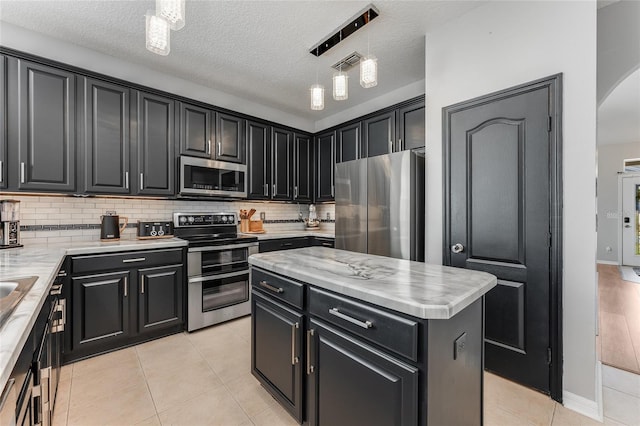 kitchen with visible vents, decorative backsplash, appliances with stainless steel finishes, dark cabinets, and light tile patterned flooring