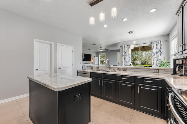 kitchen featuring light tile patterned floors, a sink, a wealth of natural light, and dark cabinets