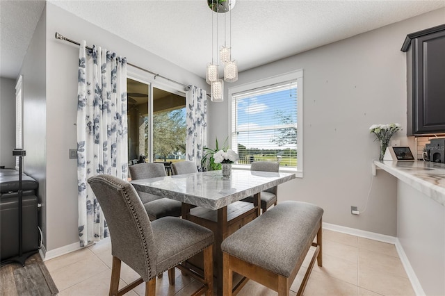 dining area featuring light tile patterned floors, a textured ceiling, and baseboards