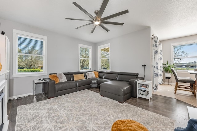 living area featuring ceiling fan, a textured ceiling, baseboards, and wood finished floors