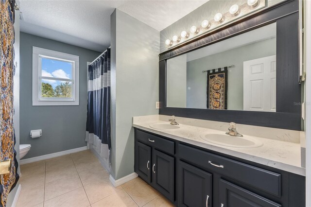 bathroom featuring toilet, tile patterned flooring, double vanity, and a sink