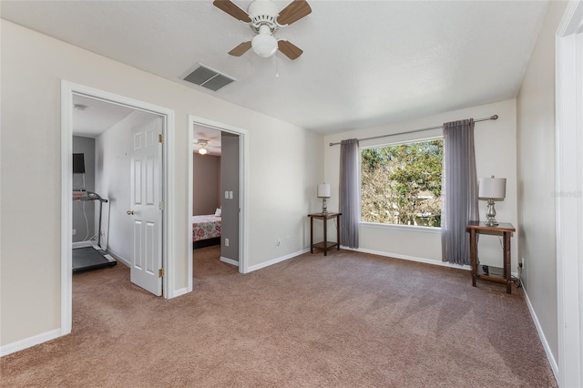 unfurnished room with carpet floors, baseboards, visible vents, and a ceiling fan