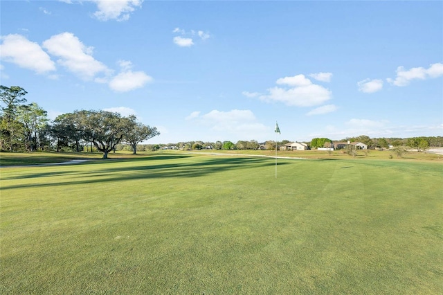 view of property's community with view of golf course and a lawn