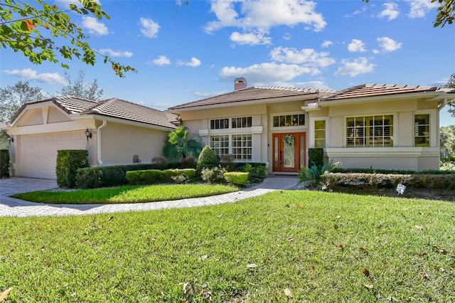 view of front facade featuring a tile roof, driveway, stucco siding, a front lawn, and a chimney