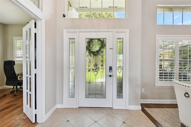 entrance foyer featuring visible vents, a high ceiling, baseboards, and light tile patterned flooring