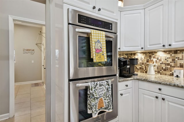 kitchen featuring white cabinets, double oven, decorative backsplash, and light tile patterned flooring