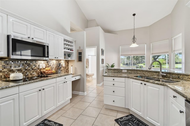 kitchen featuring light tile patterned floors, stainless steel appliances, tasteful backsplash, white cabinets, and a sink