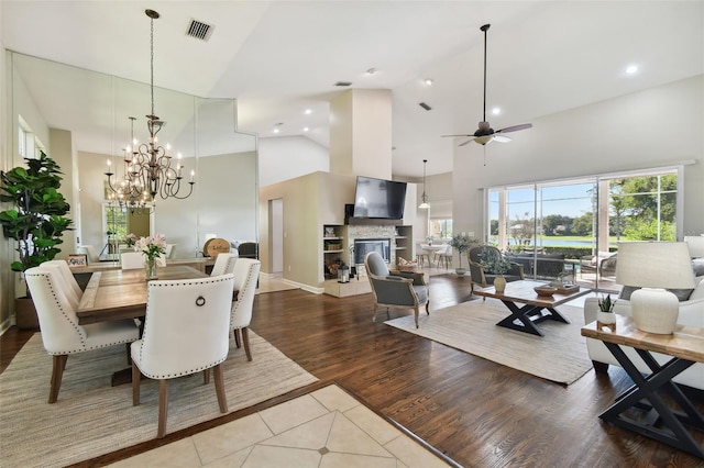 dining room with high vaulted ceiling, recessed lighting, a fireplace, wood finished floors, and visible vents