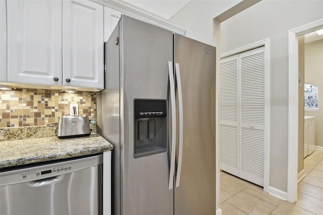 kitchen featuring light tile patterned floors, decorative backsplash, light stone counters, stainless steel appliances, and white cabinetry