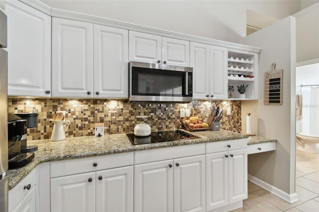 kitchen featuring white cabinets, stainless steel microwave, decorative backsplash, and black electric cooktop