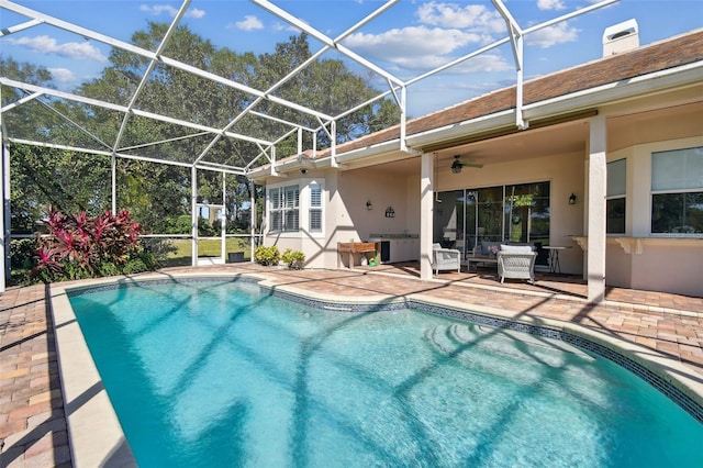 pool with a patio, glass enclosure, and a ceiling fan