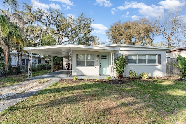 view of front of home with driveway, concrete block siding, fence, and a carport