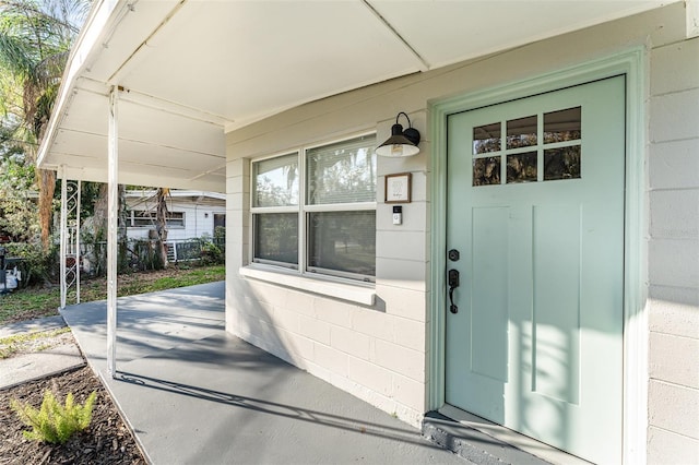 view of exterior entry with covered porch and concrete block siding