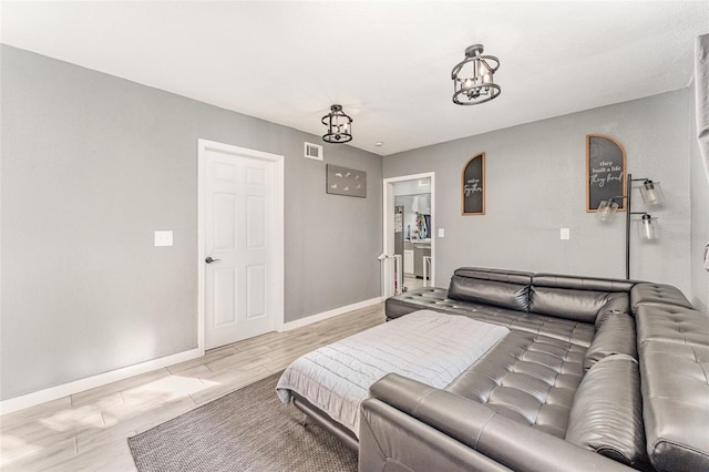 bedroom with light wood-style flooring, an inviting chandelier, visible vents, and baseboards