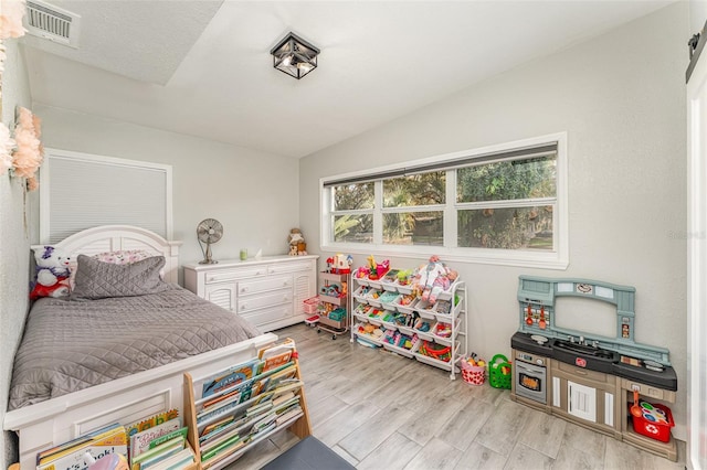 bedroom with visible vents, vaulted ceiling, and light wood-style flooring