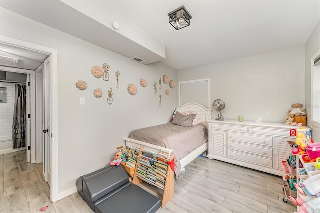 bedroom with wood finish floors, visible vents, and baseboards